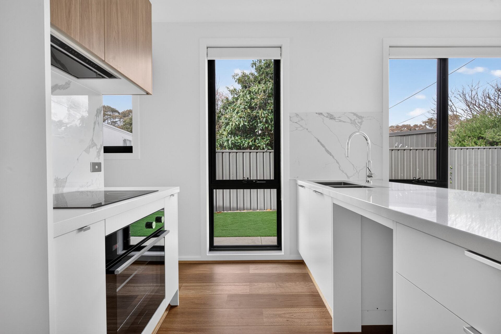 Designer kitchen with stone benchtop, timber cabinetry and marble-look splashback
