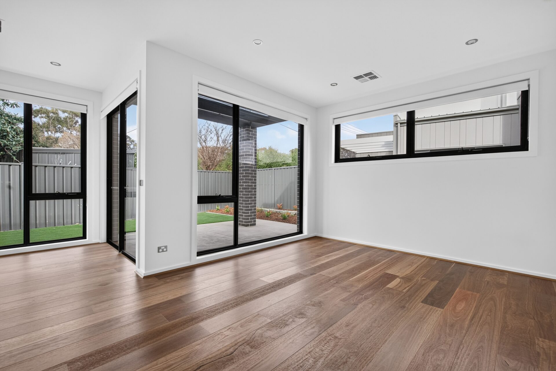Open-plan living area with timber flooring and glass-balustrade staircase